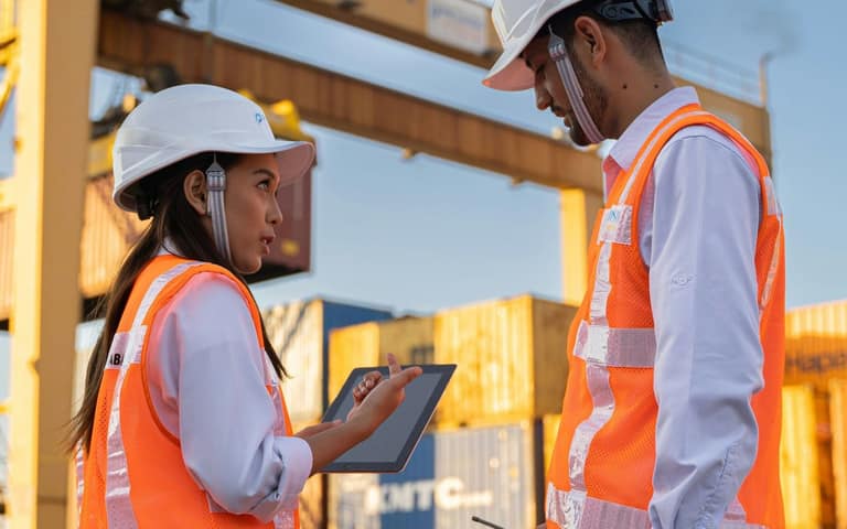 Dos profesionales revisando documentación en una tablet en la terminal de contenedores